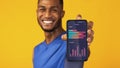 Cheerful black man demonstrating application on smartphone screen with sport activity progress