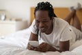 Cheerful Black Man Messaging With Friends On Smartphone While Lying On Bed Royalty Free Stock Photo