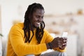 Cheerful Black Man Messaging On Mobile Phone While Relaxing At Home Royalty Free Stock Photo