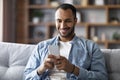 Cheerful Black Man Playing Online Games On Smartphone While Relaxing On Couch, Royalty Free Stock Photo