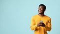 Cheerful black man using smartphone, looking at copy space Royalty Free Stock Photo