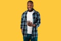 Cheerful Black Man Using Smartphone Texting Standing Over Yellow Background Royalty Free Stock Photo