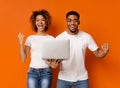 Cheerful black millennial couple with laptop screaming