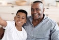 Cheerful black preteen boy taking selfie with his smiling granddad at home Royalty Free Stock Photo