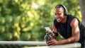 Cheerful black sporty guy chatting on phone, drinking protein Royalty Free Stock Photo