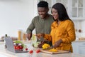 Cheerful Black Spouses Cooking Lunch In Kitchen And Checking Recipes On Laptop Royalty Free Stock Photo