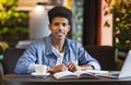 Cheerful black student doing homework at cafe