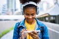 Cheerful black student girl wearing headset and using mobile smartphone Royalty Free Stock Photo