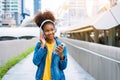 Cheerful black student girl wearing headset and using mobile smartphone Royalty Free Stock Photo