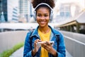 Cheerful black student girl wearing headset and using mobile smartphone Royalty Free Stock Photo