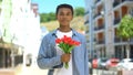 Cheerful black teen boy holding bunch of tulips, international women day gift Royalty Free Stock Photo
