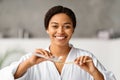 Cheerful black woman applying toothpaste to toothbrush, getting ready for oral hygiene Royalty Free Stock Photo