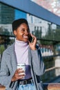 Cheerful black woman with coffee having smartphone conversation