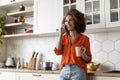 Cheerful Black Woman Drinking Coffee And Talking On Cellphone In Kitchen Interior Royalty Free Stock Photo