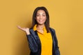 Cheerful black woman with empty open hand for advertising marketing or product placement posing on yellow background