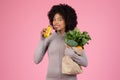 Cheerful black woman sipping juice, holding grocery bag Royalty Free Stock Photo