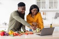 Cheerful Black Young Couple Using Laptop While Cooking Healthy Food In Kitchen Royalty Free Stock Photo