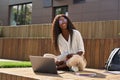 Cheerful African girl student learning using laptop, laughing, sitting outdoors. Royalty Free Stock Photo