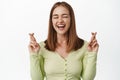 Cheerful blond girl laughs and makes wish, cross fingers optimistic, praying for good luck, wishing to pass exams Royalty Free Stock Photo