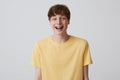 Cheerful blond young man with short haircut and metal braces on teeth wears yellow t shirt and looks happy  over white Royalty Free Stock Photo