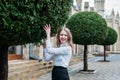 Cheerful blonde businesswoman laughs hugging a green round beautiful tree outdoors Royalty Free Stock Photo