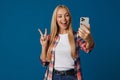 Cheerful blonde showing peace sign girl taking selfie on smartphone Royalty Free Stock Photo