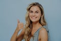 Cheerful blonde woman showing thumbs up gesture