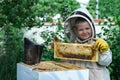 Cheerful boy beekeeper in protective suit near beehive. Honeycomb with honey. Organic food concept. The most useful organic honey