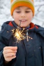 Cheerful boy with Bengal fire in hand in winter