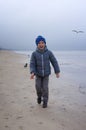 A cheerful boy feeds gulls on the seashore in winter, spring or autumn. many gulls are flying around. Cold day by the sea. Royalty Free Stock Photo