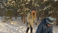 Cheerful boy and girl teenager playing in snowballs in forest at winter vacation