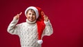 Cheerful boy in a light knit sweater and Santa hat is holding a candy cane Royalty Free Stock Photo