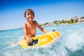 Cheerful boy riding the waves on swimming mattress