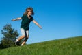 Cheerful boy running on the green grass. Happy child playing in green spring field against sky background. Freedom Royalty Free Stock Photo