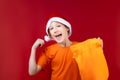 cheerful boy in a Santa hat holds a New Year`s bag with gifts in his hands Royalty Free Stock Photo