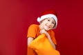 Cheerful boy in a Santa hat stuck his hand in a yellow Christmas bag and smiles Royalty Free Stock Photo