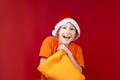 cheerful boy in a Santa hat stuck his hand in a yellow Christmas bag and smiles Royalty Free Stock Photo