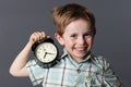 Cheerful boy showing an alarm clock for playful time concept