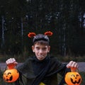 A cheerful boy in vampire costumes shows his teeth holding Jack's lanterns in his hands on a dark background Royalty Free Stock Photo