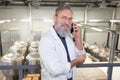 Cheerful brewer having a phone conversation at a beer plant