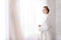 Cheerful bride standing near the window in the white room