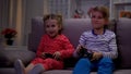 Cheerful brother and sister playing video game using console at night, leisure