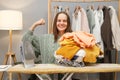 Cheerful brown haired woman wearing knitted shirt ironing clothing showing her strong hands rejoicing finished household chores Royalty Free Stock Photo