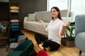 Cheerful brunette woman, shop assistant, seller in a furniture store, sitting in a lotus position between sofas and upholstered