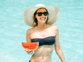 Cheerful brunette girl in a black bikini holding a watermelon in her hands and smiling Royalty Free Stock Photo