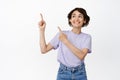 Cheerful brunette girl looks dreamy and happy, pointing fingers at upper left corner, showing banner advertisement Royalty Free Stock Photo