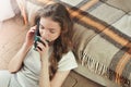 Cheerful brunette girl talking on mobile phone while sitting near couch Royalty Free Stock Photo