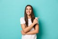 Cheerful brunette girl in white t-shirt, smiling pleased and pointing fingers at upper right corner, showing logo