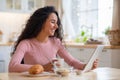 Cheerful Brunette Lady Using Digital Tablet While Having Breakfast In Kitchen Royalty Free Stock Photo