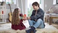 Cheerful brunette positive man with toothy smile giving surprise gift box to excited little girl. Portrait of Caucasian